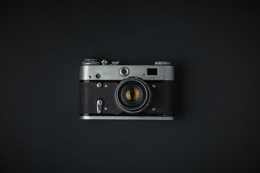 Old retro camera on the black background. Stylish background for a photo enthusiast. Flat lay