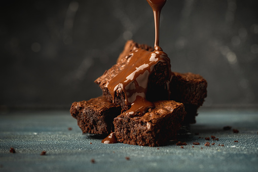 Chocolate cake slice with fudge sauce on a wooden background