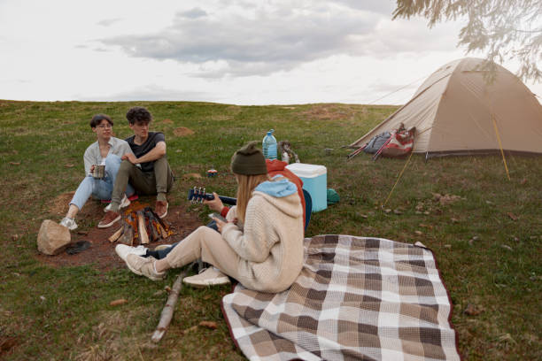 istock Young people hanging out at fire in camp site high in mountains. Playing guitar and singing. 1403510932