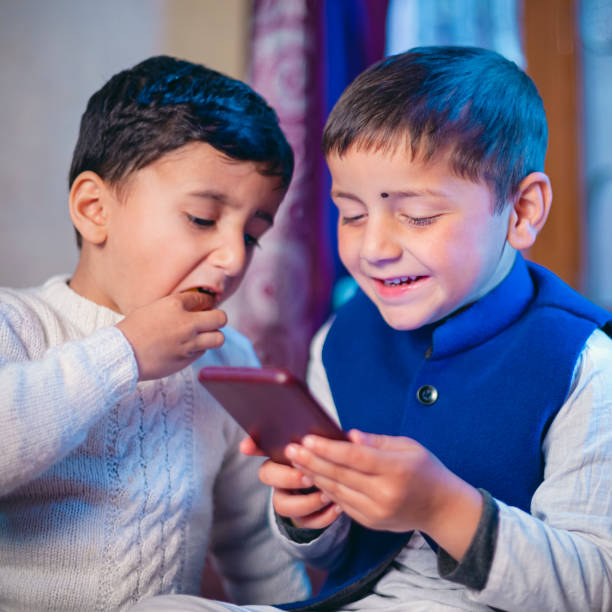дети используют и делят смартфон, сидя вместе. - iphone human hand iphone 5 smart phone стоковые фото и изображения