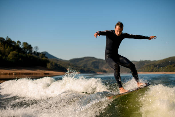 istock man in black wetsuit stands on splashing wave on a wakesurf 1403511954