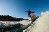 istock man wakesurfer riding down the splashing wave on blue sky background 1403512409