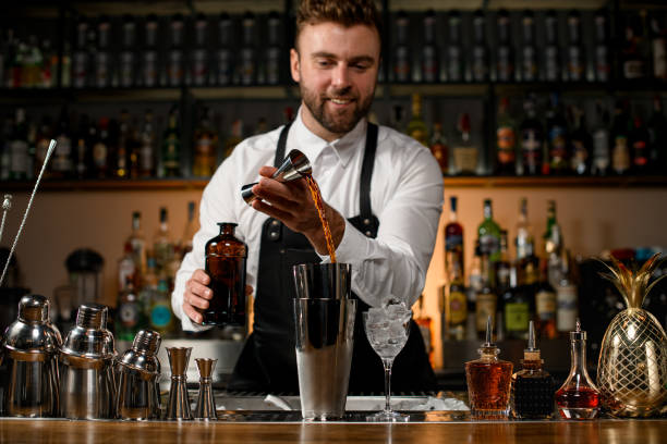 istock view on bar counter with various shakers and bottles on it and male bartender gently pours alcoholic drink into cup 1403514006