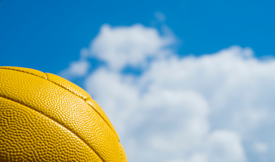 yellow volleyball against a blue sky and clouds with free space for inscriptions and texts