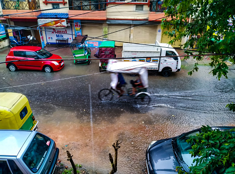 Kolkata WB India - May 11, 2021 : In the picture a woman with mask crossing the street in heavy rain. The streets are flooded and raining heavily. In Kolkata streets are flooded during heavy rain.