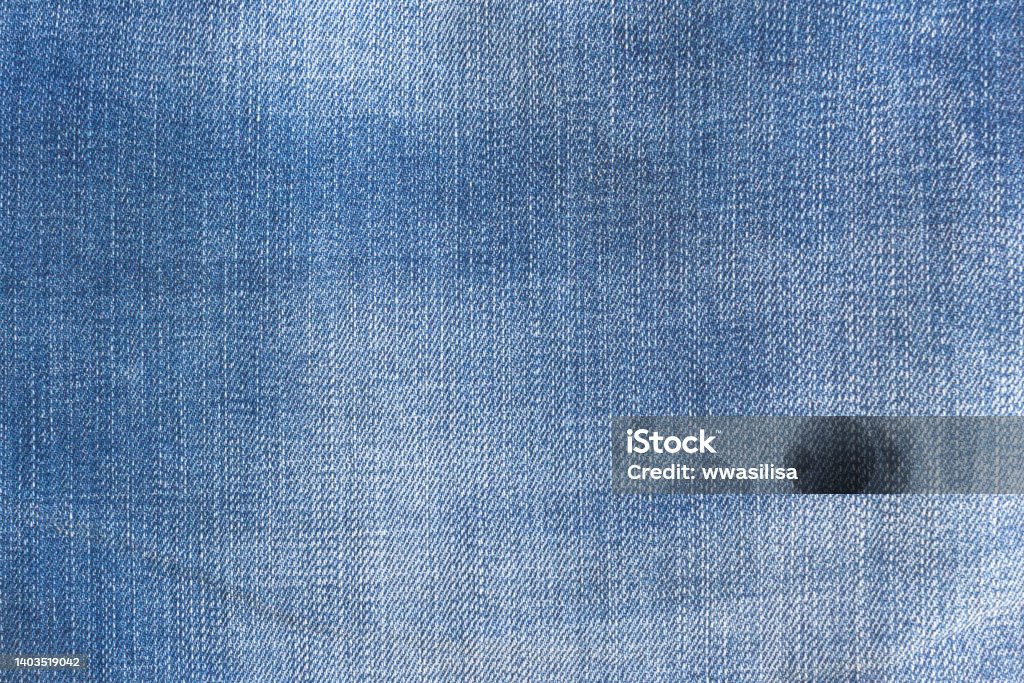 Lighter spots on the fabric are a special light scuff - a fashionable piece of clothing. blue jeans denim texture background. Lighter spots on the fabric are a special light scuff - a fashionable piece of clothing. Denim Stock Photo