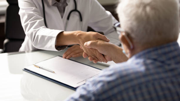 istock Senior man visiting doctor, shaking hands with young female therapist 1403523103