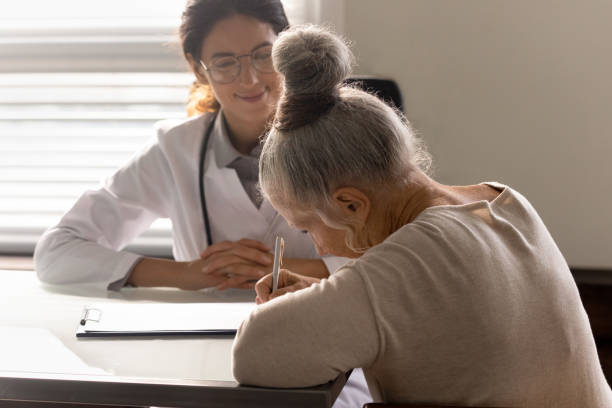 istock Old lady filling document at appointment in doctor office 1403523130
