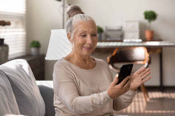 istock Happy elderly lady using smartphone at home, making video call 1403523141