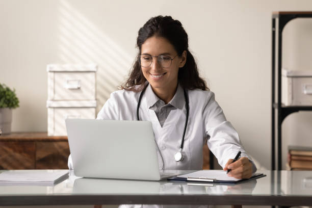 istock Happy young female GP doctor using laptop, making video call 1403523151