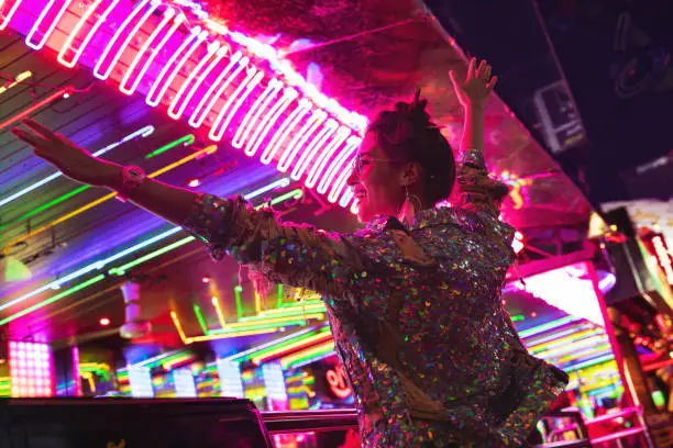 Photo of Stylish woman wearing jacket with shining sequins on the city street with neon lights