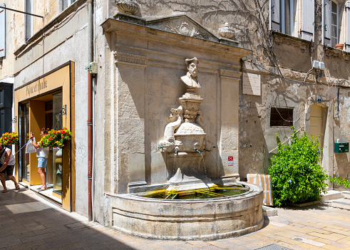 The Fontaine Nostradamus or Fountain of Nostradamus on a charming picturesque street of shops and cafes in the historic medieval village town of Saint-Remy-de-Provence in the Provence Cote d'Azur region of Southern France.