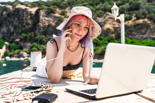 Young woman with colored hair working remotely on vacation