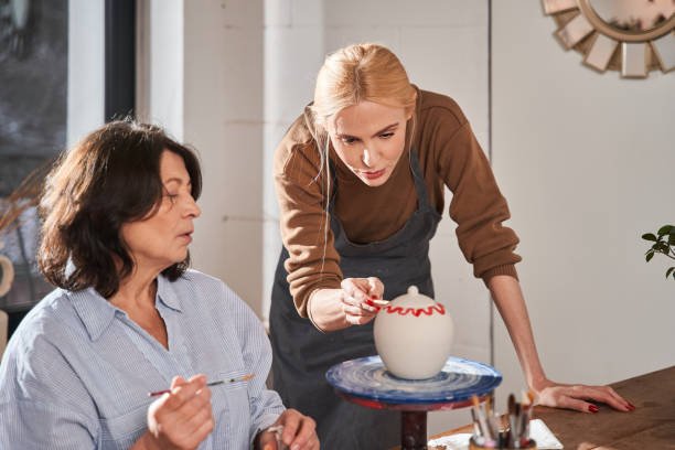 istock Skilful designer advising to her senior student while working at the pottery master class 1403529694