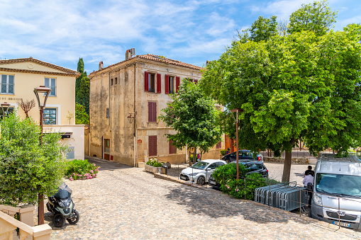 Ivy and flower covered shops and cafes near the historic town square in the medieval hilltop village of Grimaud, France, a picturesque town under the Castle of Grimaud along the French Riviera near Saint-Tropez.