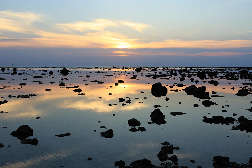 Beautiful sunset on the beach. Scenic seascape with rock during the low tide.