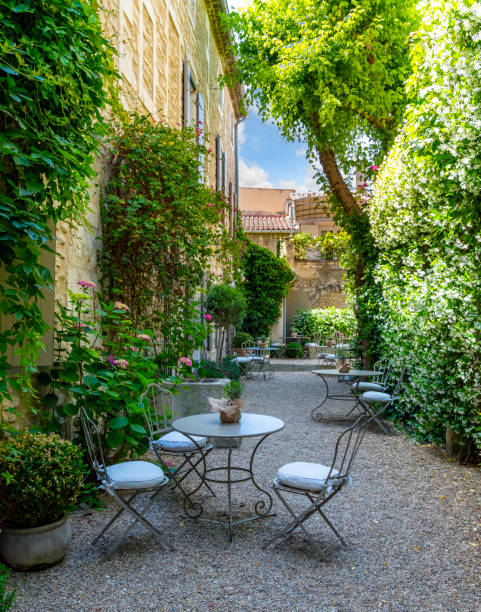 sillas y mesas listas para los comensales en un pequeño patio patio de un restaurante cafetería en el centro histórico de saint-rémy-de-provence, francia. - st remy de provence fotografías e imágenes de stock