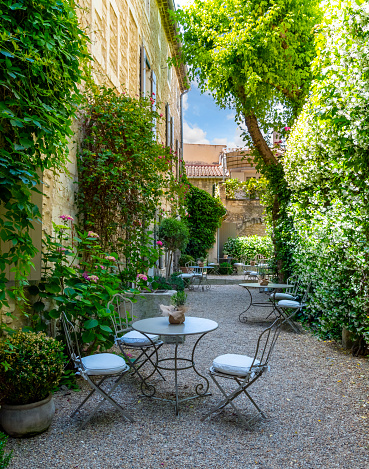 Chairs and tables ready for diners in a small courtyard patio of a restaurant cafe in the historic center of Saint-Rémy-de-Provence, France.