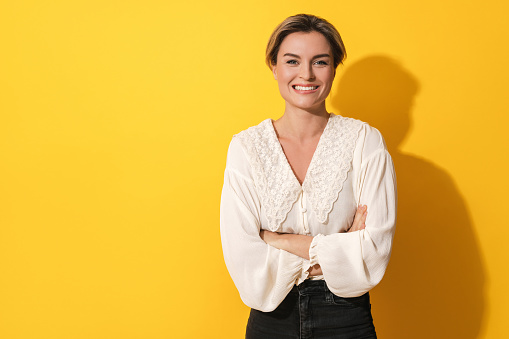 Portrait of young cheerful woman on yellow background