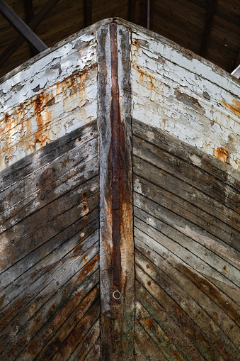 A head-on image of the bow of an old boat pulled up on land.