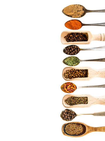 spoons with herbs and spices on white background