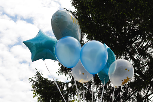 Defocus bunch of bright blue balloons on nature background, space for text. Banner design. Photo zone with balloons. Boy's birthday decor. Festive decor. Balloons. Hello baby, newborn. Out of focus.