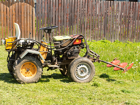 A small tractor with a mower attachment for grass standing on a farm .agricultural machinery.