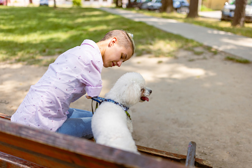 Girl with a disability (phocomelia) having fun with her dog in the park.  She was born without hands.