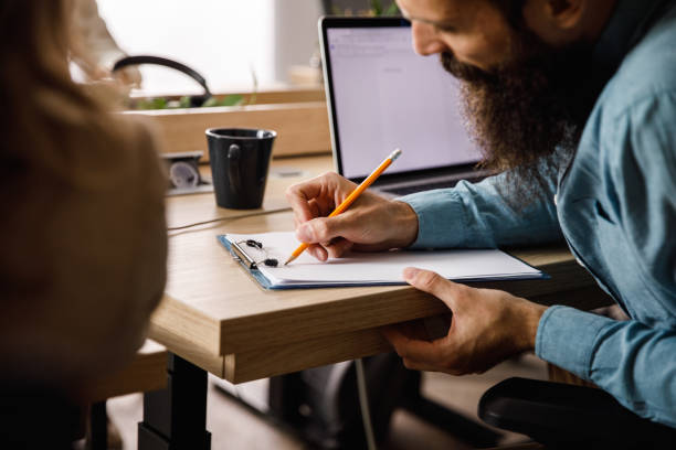 istock Hipster businessman writing notes while working on a project with a colleague 1403555065