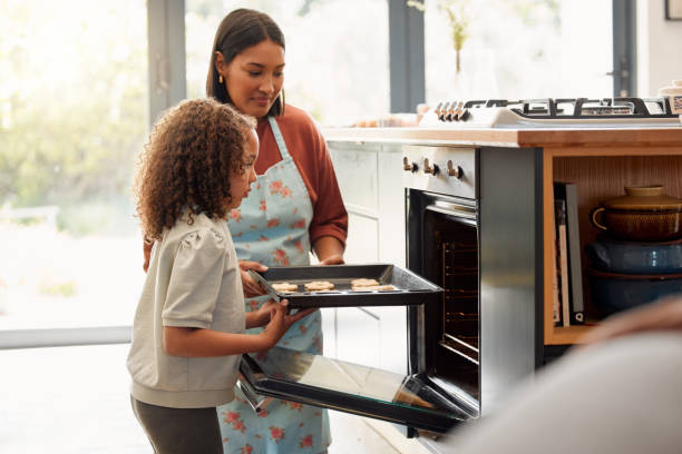 deux femmes ne font que cuisiner et s’amuser dans une cuisine ensemble. une jeune mère monoparentale métisse qui crée des liens avec sa fille tout en lui enseignant ses compétences domestiques à la maison - cookie mother 30s parent photos et images de collection