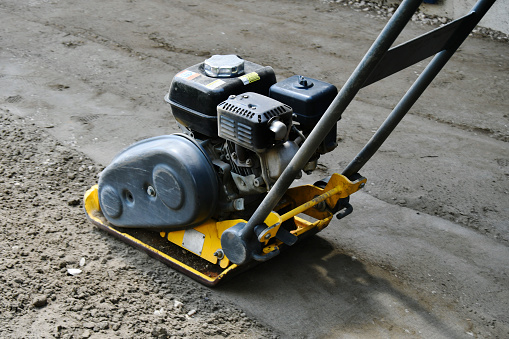 A close up image of a vibrating soil compactor used to compact soil in preparation for paving stones.