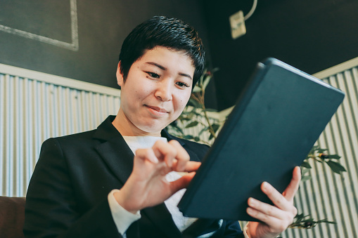 Asian short-haired businesswoman uses a tablet at office