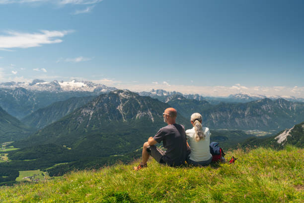 widok z tyłu dojrzała para robiąca sobie przerwę podczas wędrówki wysoko w górach - european alps women summer outdoor pursuit zdjęcia i obrazy z banku zdjęć