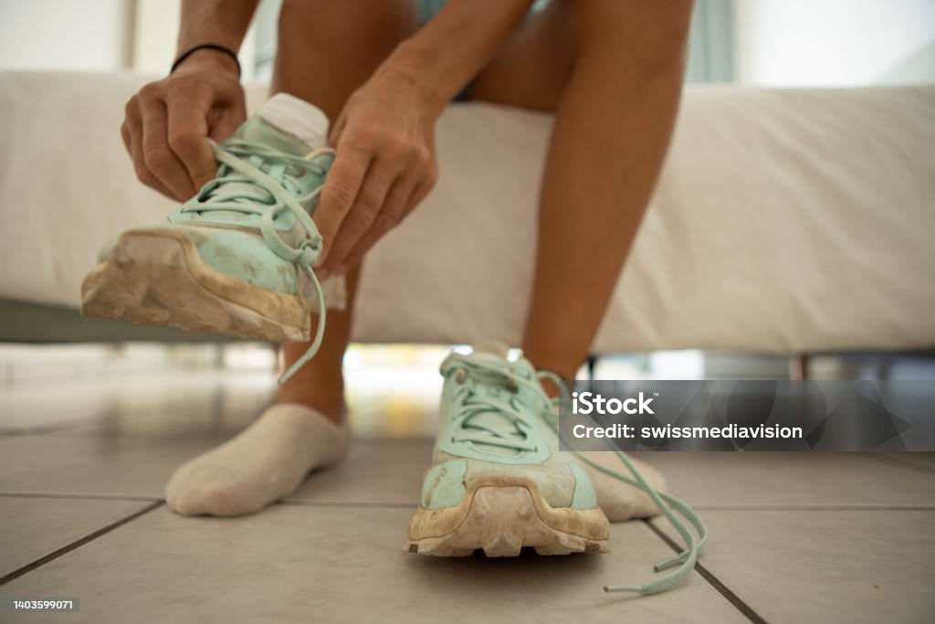 Woman getting ready for a workout Close up of a woman putting her sport shoes on Getting Dressed Stock Photo