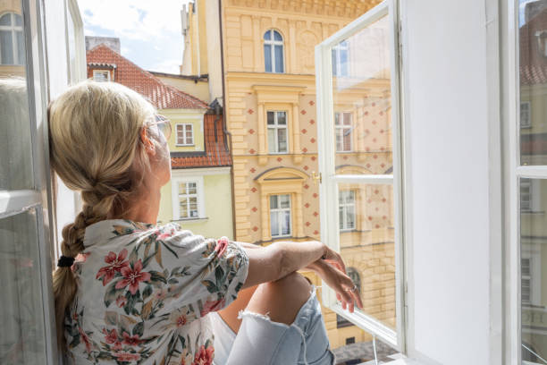 istock Young woman sits on balcony looking at the cityscape 1403600568