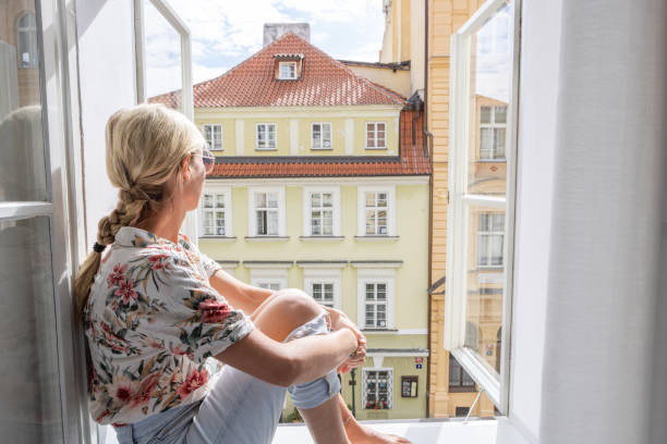 istock Young woman sits on balcony looking at the cityscape 1403600569