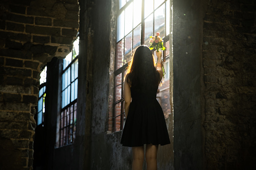 Woman in a destroyed building looking sunlight