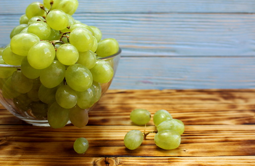 Green grapes lie in a glass bowl.