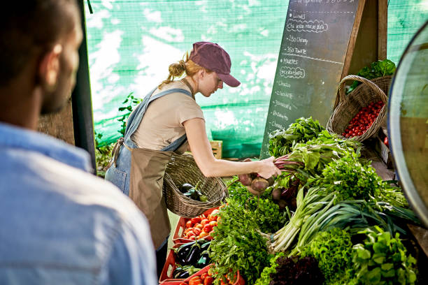 istock Young woman arranging fresh organic vegetables on display 1403606840