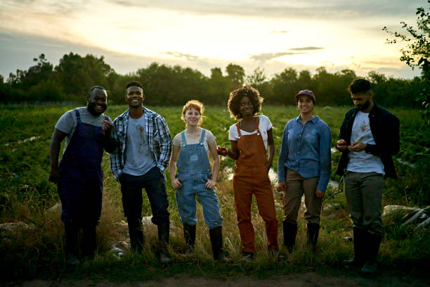 Diverse group of farm workers standing outdoors at dusk