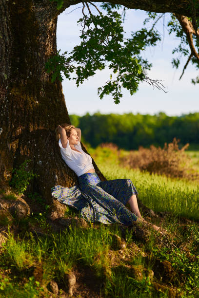 istock Young woman posing at sunset by an oak tree 1403608909