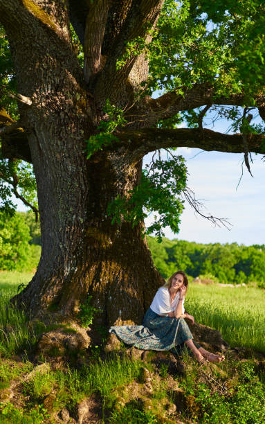 istock Young woman posing at sunset by an oak tree 1403608921