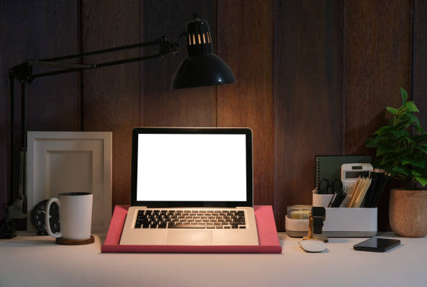 istock Front view laptop computer with blank screen, picture frame, coffee cup and potted plant on white table. 1403609748