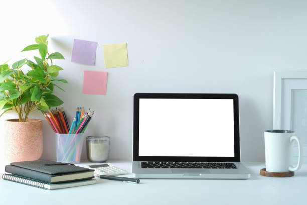 istock Computer laptop with empty screen, houseplant, picture frame and stationery on white table. 1403609776