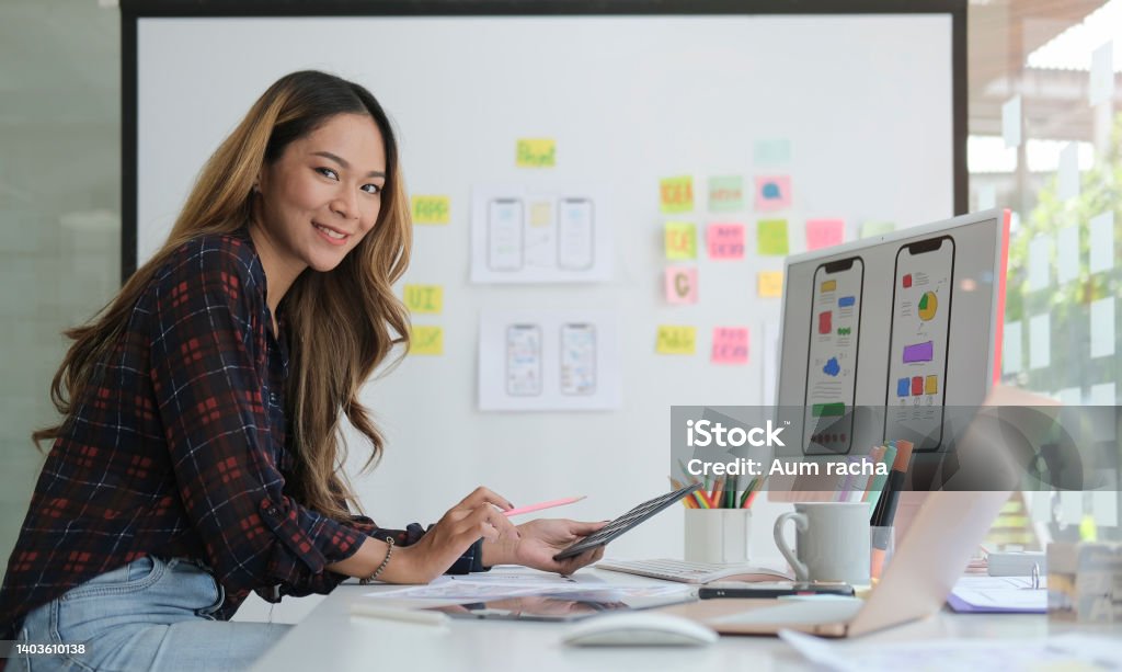 Young creative woman working and designing user interface for website and application at modern workplace. User Experience Stock Photo