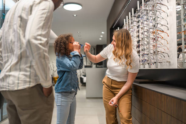 istock Friendly Female Optician Using her Hands to Adjust Eyeglasses on Girl 1403610917