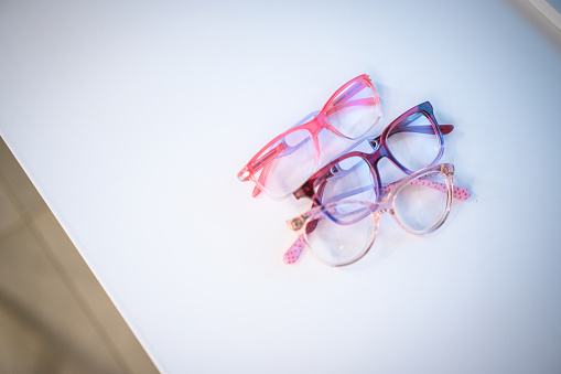 Close up of trending and colorful eye glasses frames. Pink, purple and baby pink frames on top of white background.