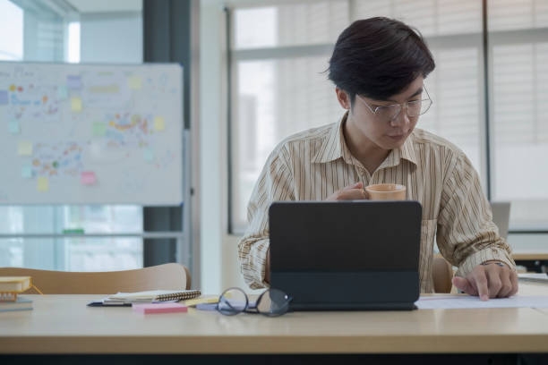 istock Focussed young businessman using computer tablet and checking financial reports at office desk. 1403611414