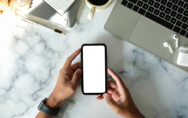 istock Above view man holding smart phone with white empty screen on office desk.