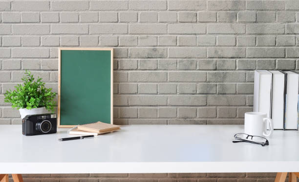 istock Creative workplace with green chalkboard, camera, coffee cup and books on white table. Copy space for your information content. 1403612271